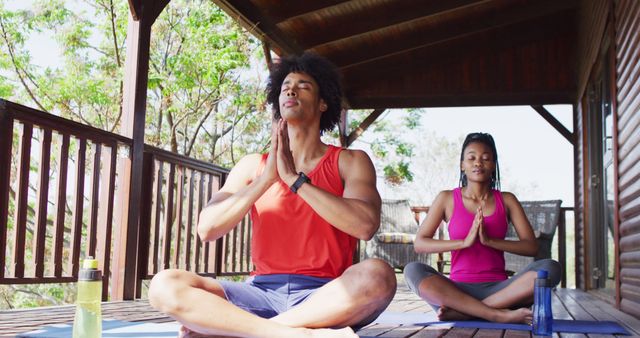 Happy african american couple doing yoga and meditating in log cabin, slow motion. Lifestyle, domestic life, countryside and nature concept.