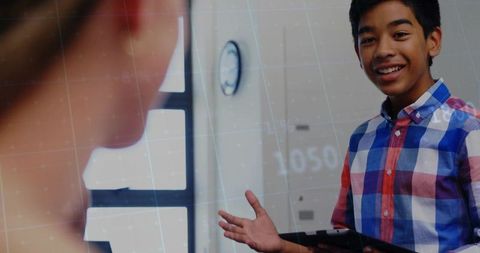 Teenage Boy Holding Tablet Engaging in Classroom Discussion