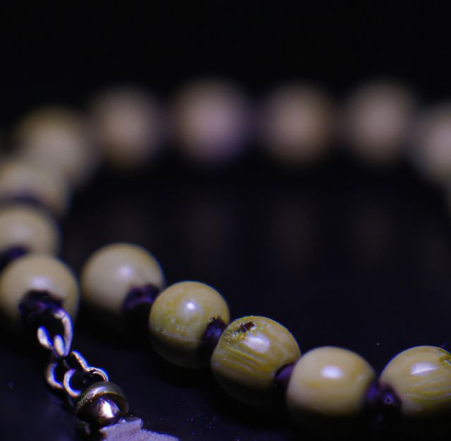 Close up of beige rosary with cross on black background. Religion, faith and prayer concept.