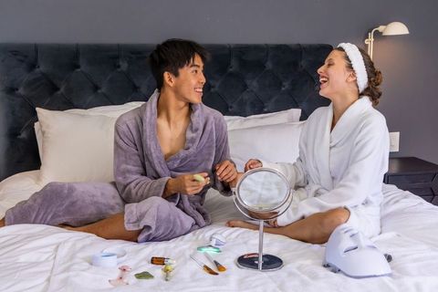 Couple enjoying at-home spa night wearing bathrobes while sharing skincare ritual on bed