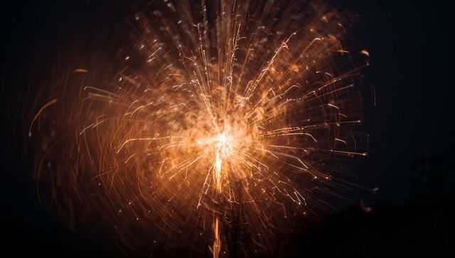 Golden firework burst brightening night sky with starburst pattern