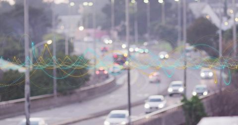 Urban highway carrying cars moving at dusk with colorful waveform data overlay