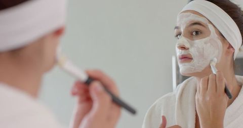 Woman Applying Facial Mask in Minimalist Bathroom Mirror Reflection