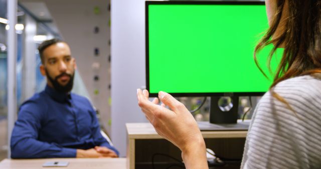 Professionals engaged in job interview at modern office with green screen computer. Useful for illustrating business meetings, hiring processes, discussions, and office environments.
