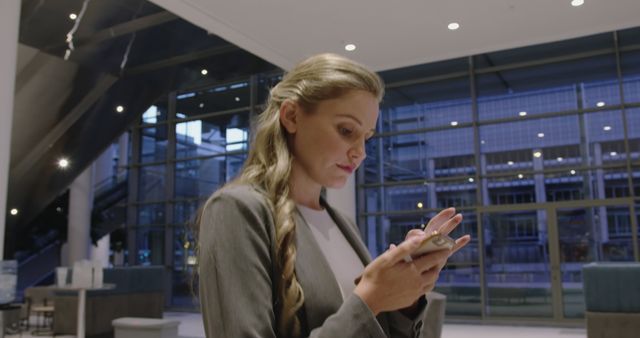 Businesswoman Checking Smartphone in Modern Office Lobby - Download Free Stock Images Pikwizard.com