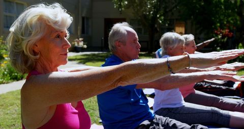Seniors Practicing Yoga Outdoors in Sunlit Garden