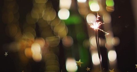 Sparklers burning with star confetti and golden bokeh lights for festive celebrations
