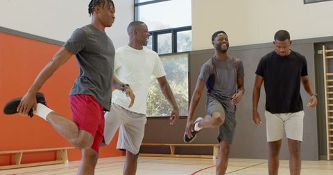 African american male basketball teammates warming up and stretching before practice