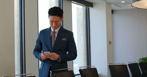 Young Businessman Engaging with Smartphone in Modern Office