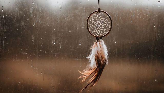 Dreamcatcher with Feathers Against Rainy Window Background