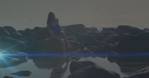 Tranquil Coastal Reflections of Woman on Rocky Shoreline at Dusk