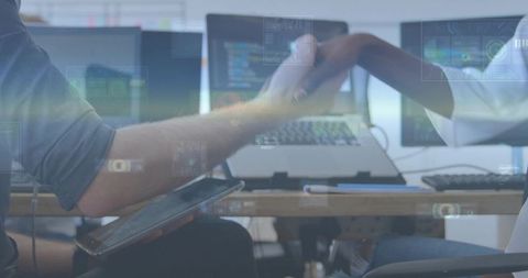 Tech startup team shaking hands over laptop screens sealing partnership and collaboration deal