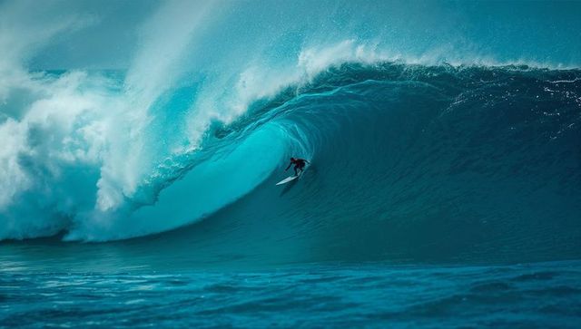 Surfer mastering powerful turquoise wave with skill and precision