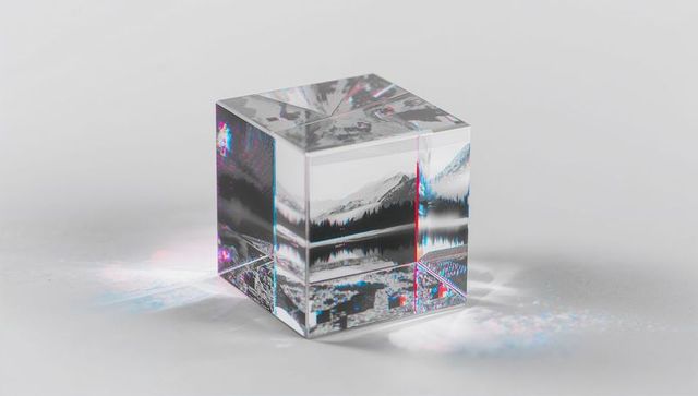 Reflecting crystal cube refracting monochrome mountain-lake scene with prism dispersion