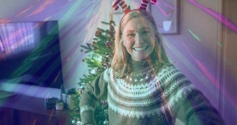 Smiling woman taking christmas selfie in fair isle sweater with striped antler headband