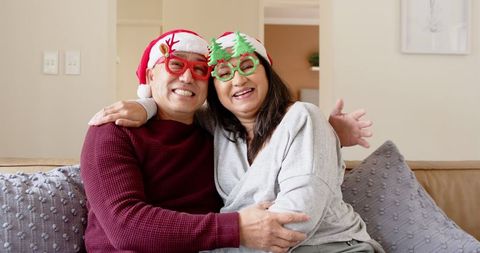 Joyful Couple Embracing with Santa Hats and Festive Glasses