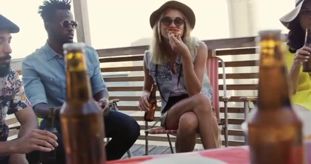 Group of friends sitting on a rooftop eating pizza and drinking beer, having a fun and relaxed time together. Suitable for promoting social events, gatherings, summer parties, or products related to casual dining, beverages, and outdoor entertainment. Captures youthful spirit and camaraderie.