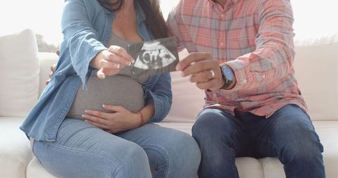 Expectant couple celebrating with ultrasound in cheery living room