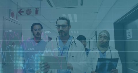 Doctors analyzing clipboard data in hospital corridor with overlay graphs