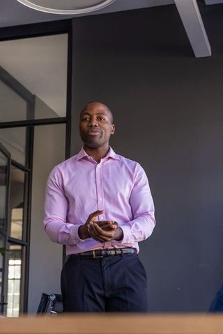 Confident businessman in modern office holding smartphone