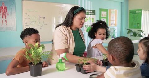 Teacher guiding children planting seedlings during classroom hands-on science lesson