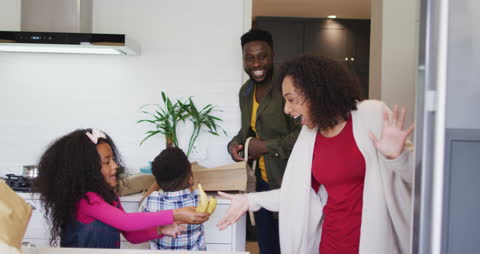 Happy Family Unpacking Groceries in Modern Kitchen