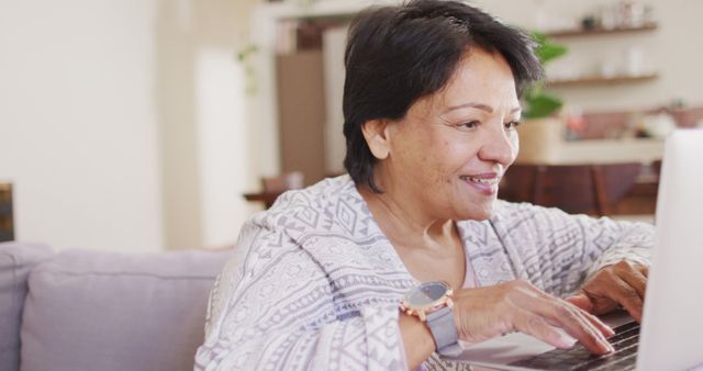 African american senior woman using laptop sitting on the couch at home. retirement lifestyle living concept