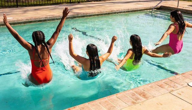 Four teens jumping into pool in colorful swimsuits splashing sunlight backyard friends joy