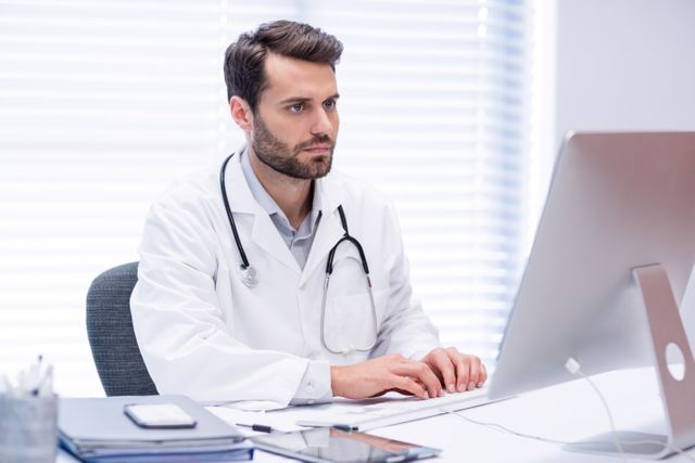 Male doctor working on personal computer in clinic