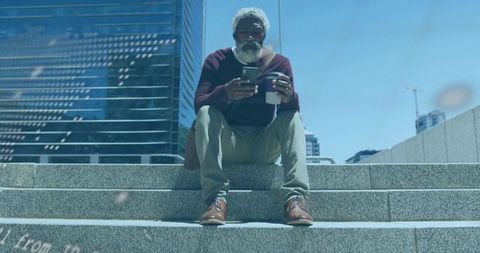Urban professional sitting on steps checking smartphone holding coffee and crossbody bag