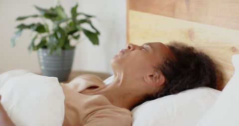 Woman Relaxing on Bed Next to Potted Plant for Tranquil Atmosphere