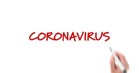 Hand writing 'coronavirus' in red on white surface