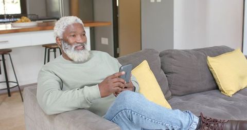 Senior Man Relaxing on Couch Looking at Smartphone
