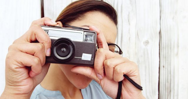 A middle-aged Caucasian woman is taking a photograph with a vintage camera, with copy space. Her focus and the retro equipment suggest a passion for classic photography or capturing moments in a traditional way.