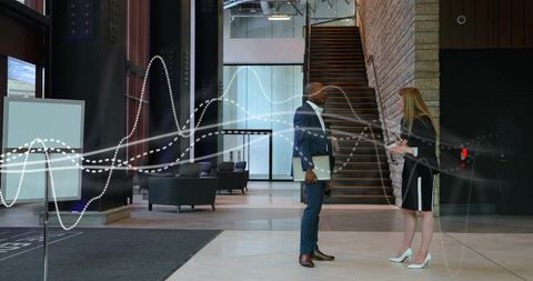 Business colleagues discussing documents in modern office lobby with digital data overlay