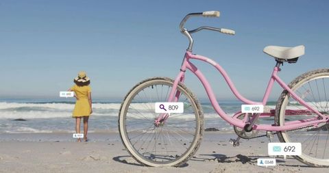 Woman Relaxing at Beach with Pastel Pink Bicycle
