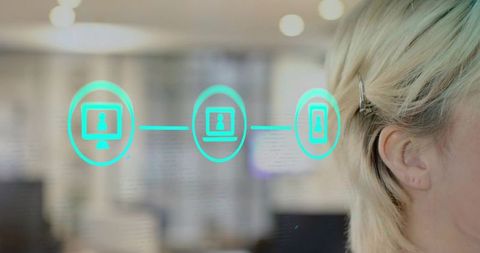 Female professional viewing teal digital connectivity icons on glass in open-plan office