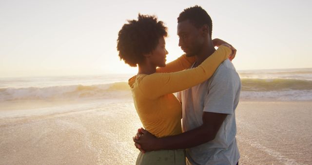 Smiling african american couple embracing in water on sunny beach. healthy, active family beach holiday.