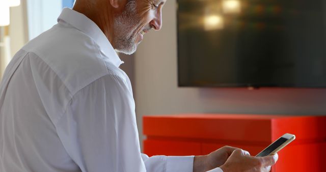 Smiling Mature Man Using Smartphone Indoors with Modern Decor - Download Free Stock Images Pikwizard.com