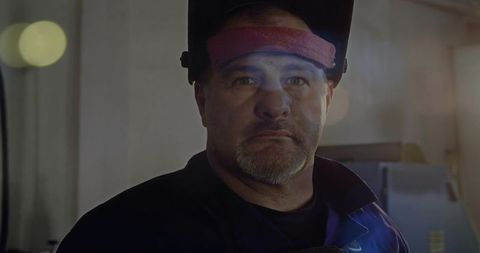 Welder in Workshop Lifting Shield with Atmospheric Lens Flare