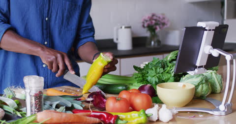Man Cooking with Fresh Vegetables Using Tablet for Recipe