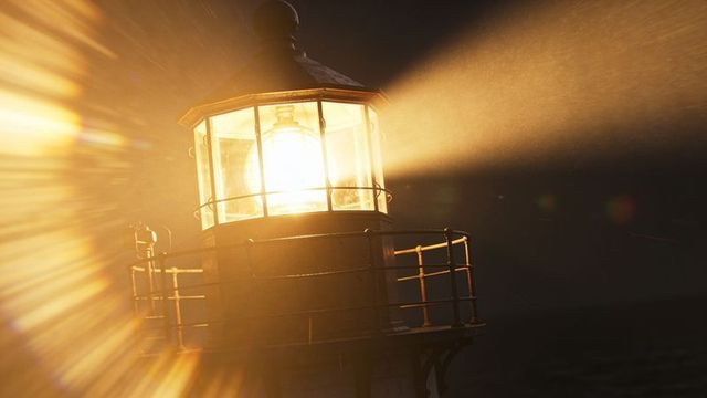 Shining lighthouse beacon projecting golden light beams through misty night sea horizon