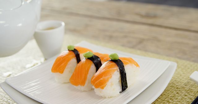 A plate of salmon nigiri sushi is presented on a wooden table, with copy space. Sushi is a traditional Japanese dish that has gained worldwide popularity for its fresh flavors and artistic presentation.