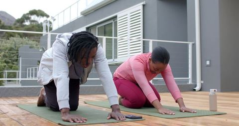 African American couple practicing partner yoga on balcony deck for wellness and balance