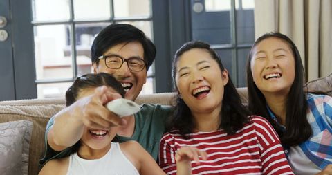 Happy Asian Family Laughing Together on Sofa