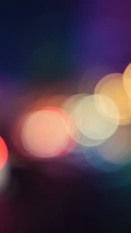 Vertical video showing colorful bokeh lights dancing across cinematic urban night