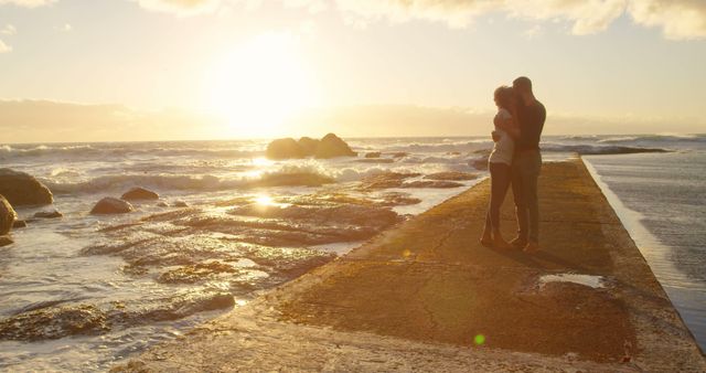 Romantic diverse couple embracing and kissing on pier at sunrise, copy space. Summer, vacation, romance, love, relationship, free time and lifestyle, unaltered.