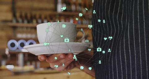 Barista holding cup and saucer with digital health network overlay in coffeehouse