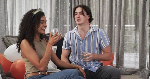 Couple Celebrating Birthday Toast in Living Room with a Smile