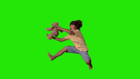 Energetic Boy Jumping with Teddy Bear on Green Screen